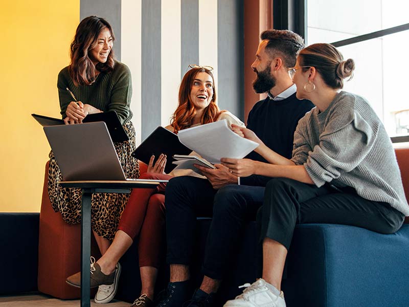 A group of people sat near a large window in their office